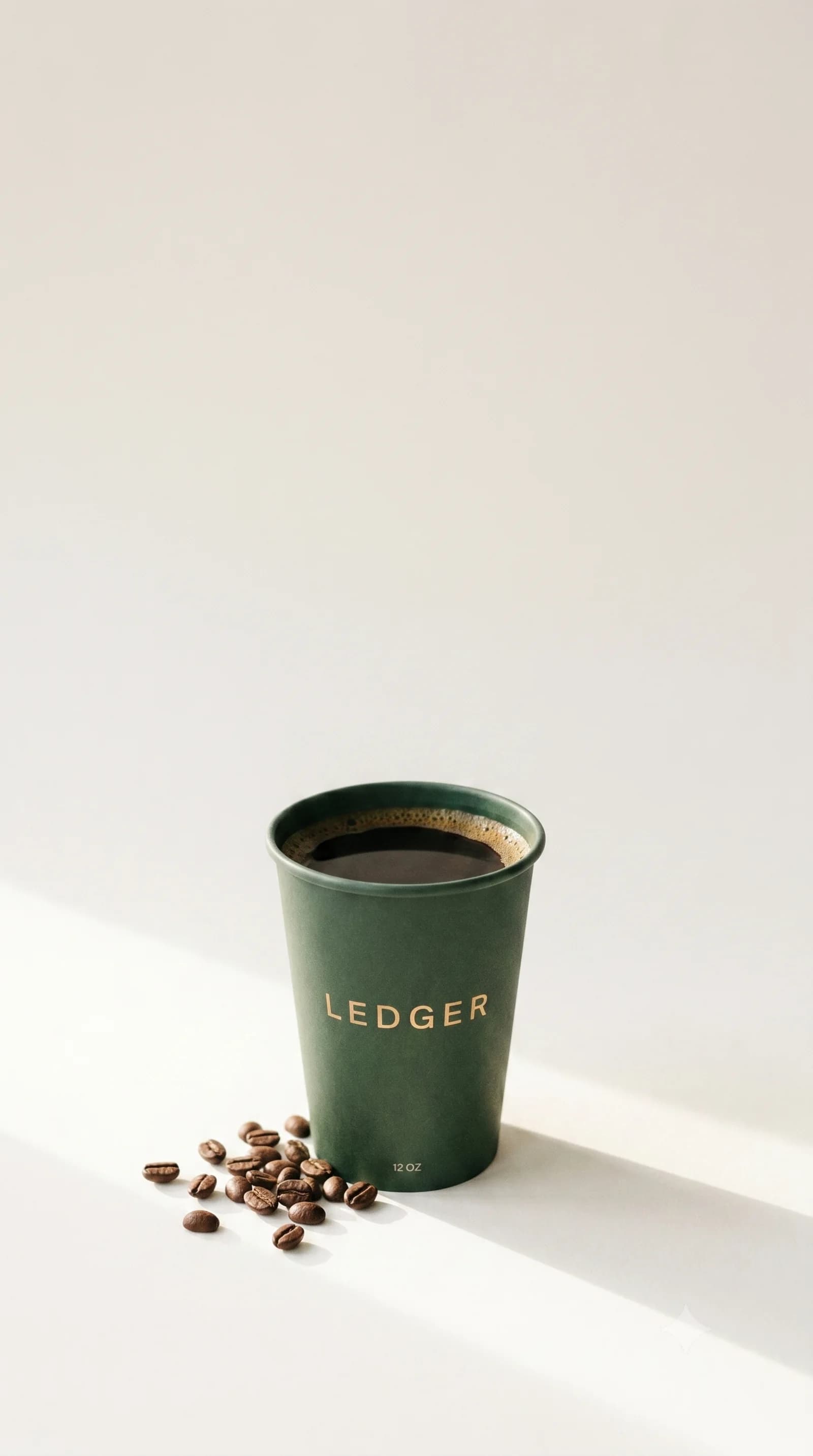 A LEDGER coffee in the bottle-green house cup, with roasted beans